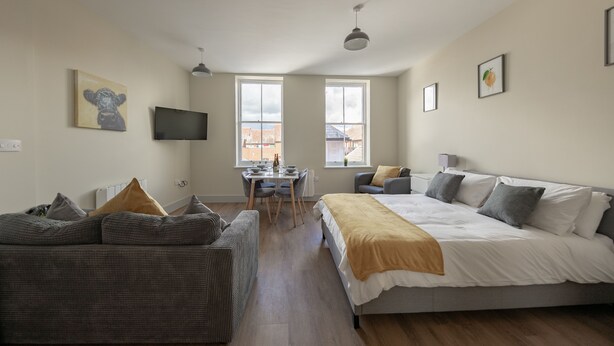 Une chambre moderne avec un grand lit, un canapé, un bureau et une télévision.