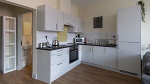 Une cuisine moderne avec des meubles blancs, un four à micro-ondes, un four traditionnel et un évier.