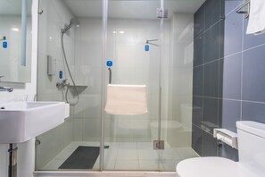 Une salle de bain moderne avec une douche à parois de verre, un lavabo blanc et des toilettes.