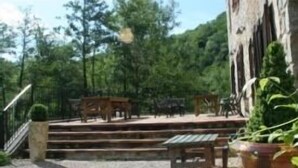 Une cour extérieure dotée d’un sol en pierre, de bancs en bois et d’un escalier menant à un bâtiment.