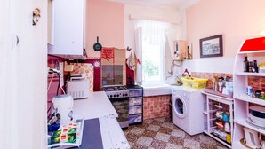 Una cucina compatta con lavatrice, fornello e finestra con tende.