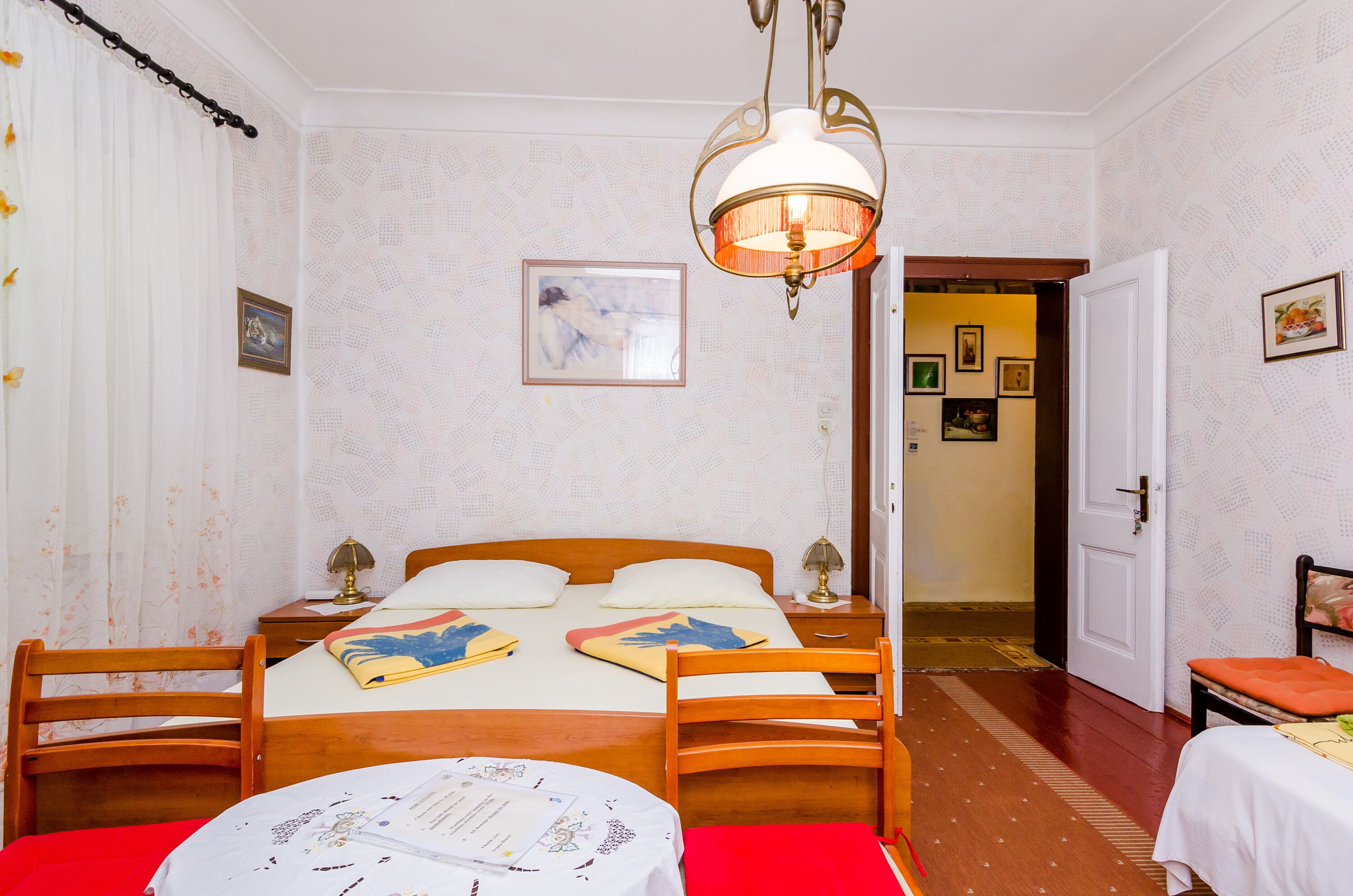 A neatly arranged bedroom with a bed, bedside tables, a chair, and a small table with papers.