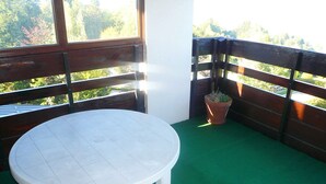 A small outdoor area with a white table and a potted plant.