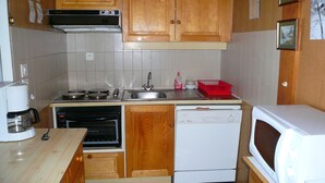 A compact kitchen with wooden cabinets, a built-in stove, a dishwasher, and a microwave.
