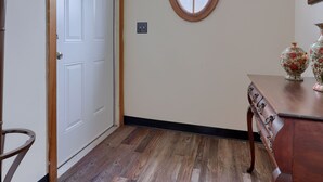 A hallway with a wooden floor, a white door, a round window, and a table with decorative items. - Spacious 4BR Stratton House: A Historic Downtown Stay Backing to Culp's Hill (Gettysburg)