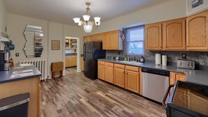 A modern kitchen with wooden cabinets, a built-in refrigerator, a dishwasher, and a window with blinds. - Spacious 4BR Stratton House: A Historic Downtown Stay Backing to Culp's Hill (Gettysburg)