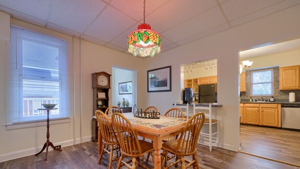 A dining area with a wooden table and chairs, a chandelier, and a view into the kitchen. - Spacious 4BR Stratton House: A Historic Downtown Stay Backing to Culp's Hill (Gettysburg)