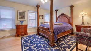 A four-poster bed with a wooden headboard, a blue patterned rug, and a wooden nightstand with drawers. - Spacious 4BR Stratton House: A Historic Downtown Stay Backing to Culp's Hill (Gettysburg)