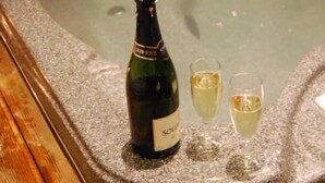 Un jacuzzi con una botella de vino Sol y Sol y dos copas de vino.