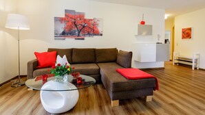 Ein modernes Wohnzimmer mit einem Ecksofa, einem Glastisch und einer roten Decke.