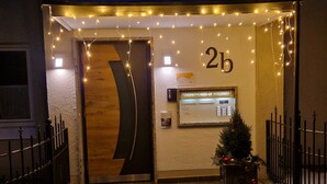 Ein Hotel Eingang mit einer Holztür, einer kleinen Weihnachtstanne und einem Schild mit der Zimmernummer '2b'.
