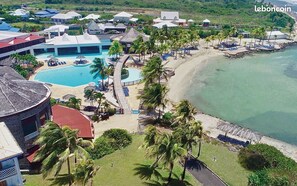 Relax by the resort's central pool surrounded by palm trees and lounge areas, with access to a sandy beach.