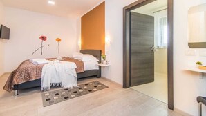 A modern bedroom with a bed, bedside table, and a large mirror. - Villa Dolores (Vrsar)
