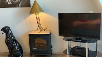 Ein Wohnzimmer mit Fernseher, kleinem Holzofen und einer schwarzen Hunde-Figur.