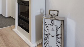 Ein Flur mit einem weißen Kamin, einer Uhr und einem Spiegel an der Wand.