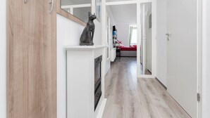 Ein Flur mit einem Holzschrank, einer Statue und einem roten Bett im Hintergrund.