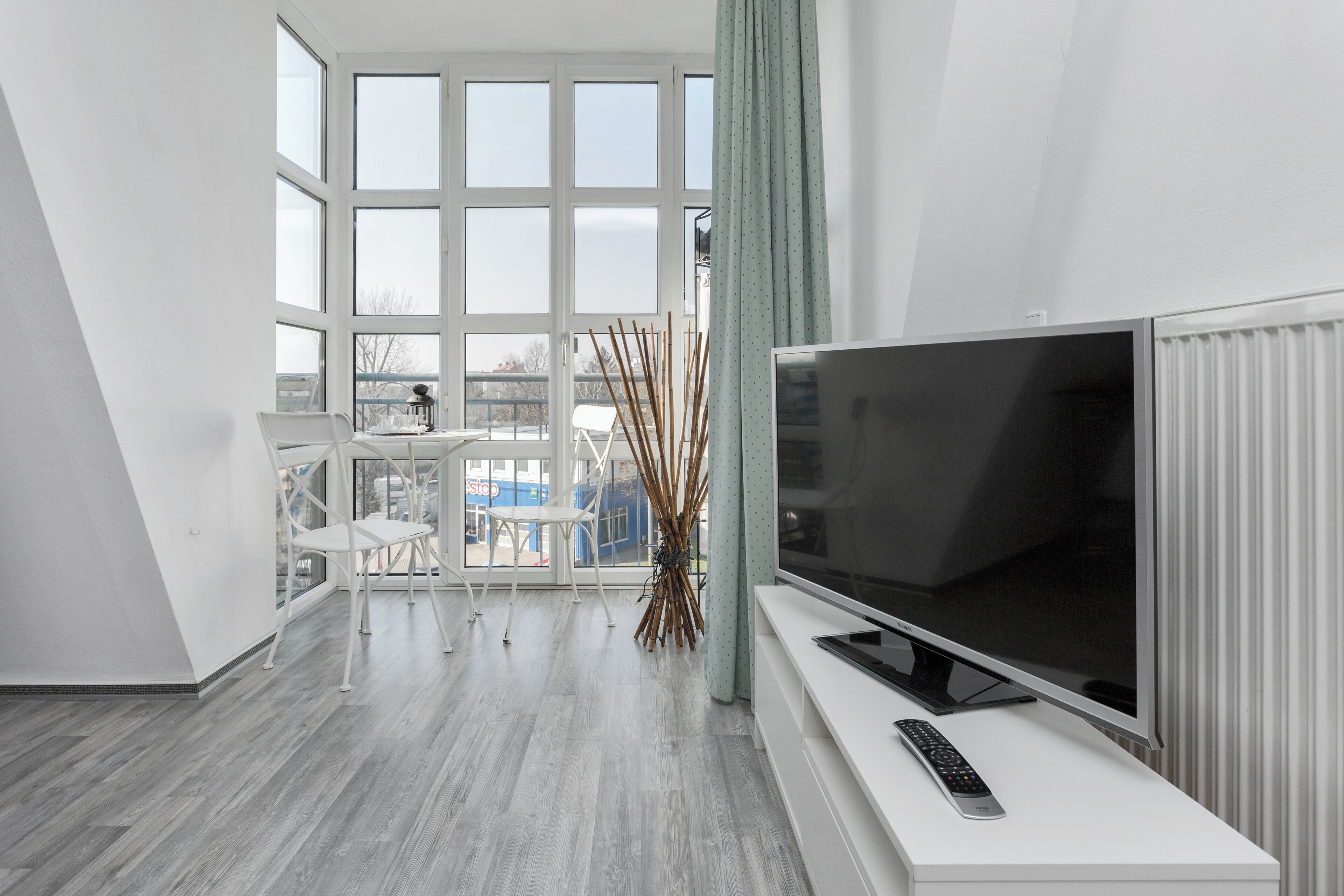 Ein modernes Wohnzimmer mit großem Flachbildfernseher, einem weißen Sofa und einem Esstisch mit Stühlen.