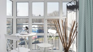 Een lichte kamer met grote ramen, een witte tafel en stoelen.