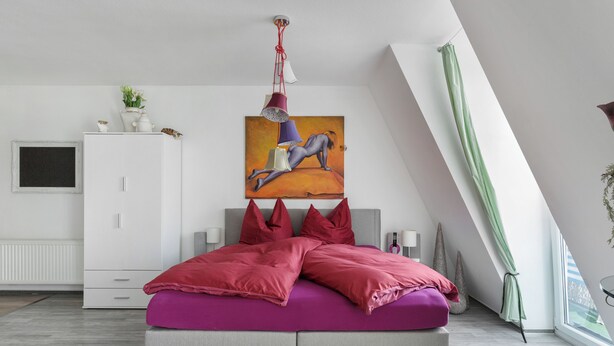 Een moderne slaapkamer met een bed, een schilderij, een kledingkast en een raam.
