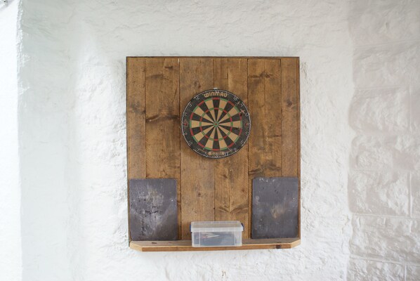 Ein Dartboard, das an einer Holzplatte an einer weißen Wand befestigt ist.