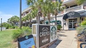 A Starbucks sign with a 'CREPES' sign in front, a brick building, and palm trees. - Reba’s Retreat – A Charming Seacrest Beach Escape (Seacrest)
