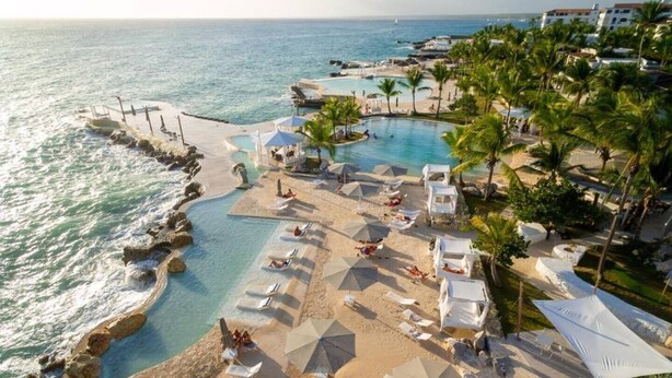 Ein Resort mit Pool, Strandbereich und Meerblick.