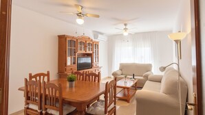 Un comedor con mesa y sillas de madera, televisor y aparador.