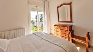 Un dormitorio con una cama grande, un aparador de madera, un espejo y una ventana con persianas.