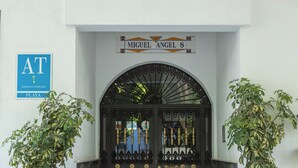 Entrada de un edificio con un cartel que dice 'Miguel Angel 8' y un letrero azul que indica 'AT' y 'EDIFICIO/COMPLEJO PLAYA'.