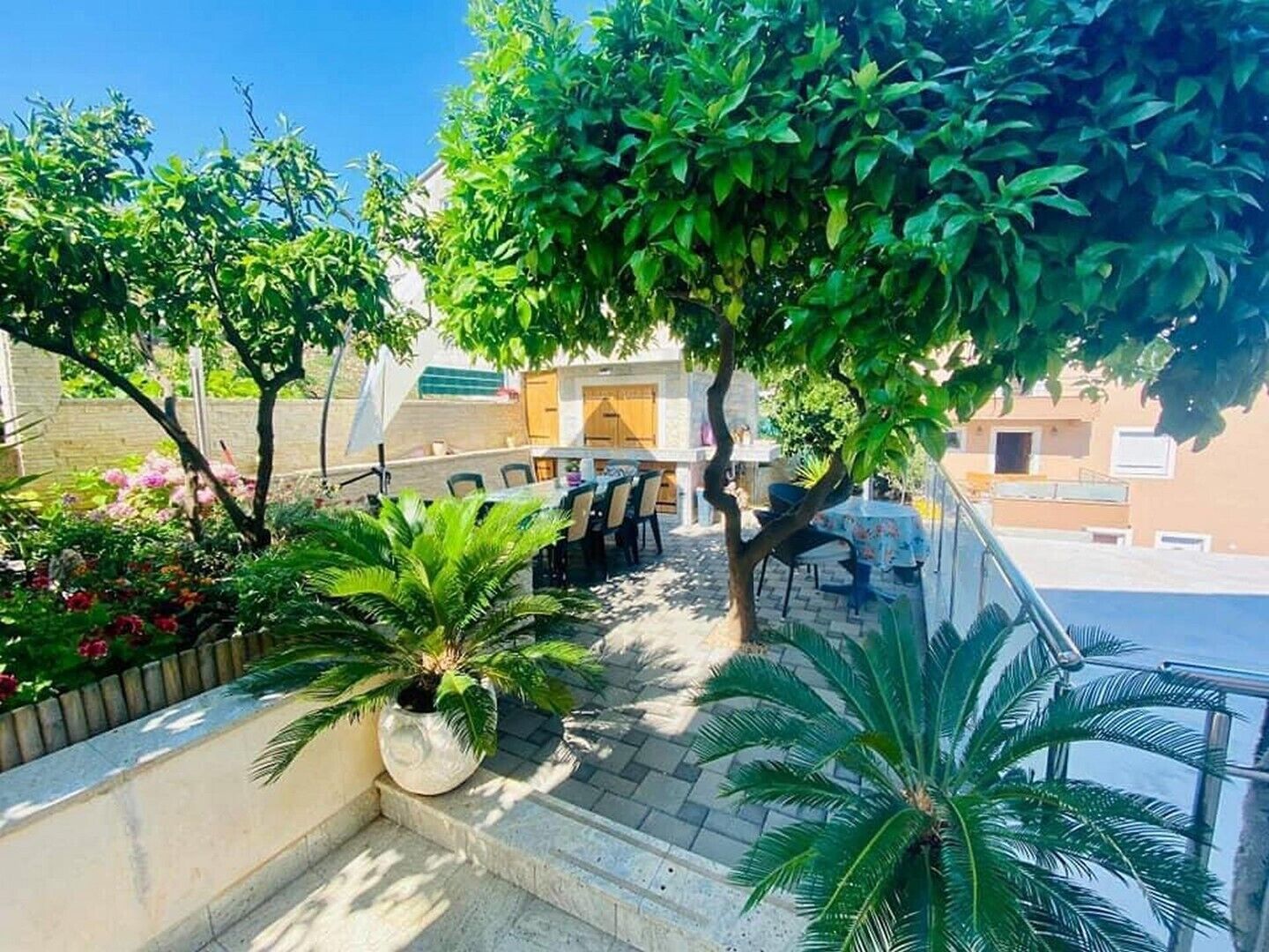 Ein Innenhof mit Außenbestuhlung, einer Palme und einem Gebäude im Hintergrund.