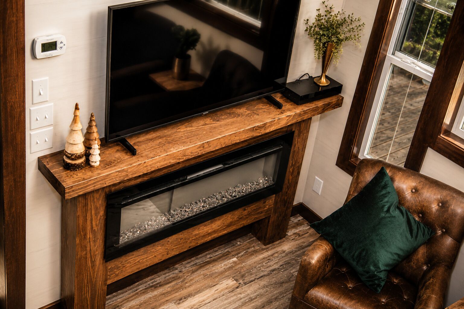 A wooden entertainment center with a flat-screen TV, decorative items, and a fireplace below.