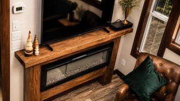A wooden entertainment center with a flat-screen TV, decorative items, and a fireplace below.