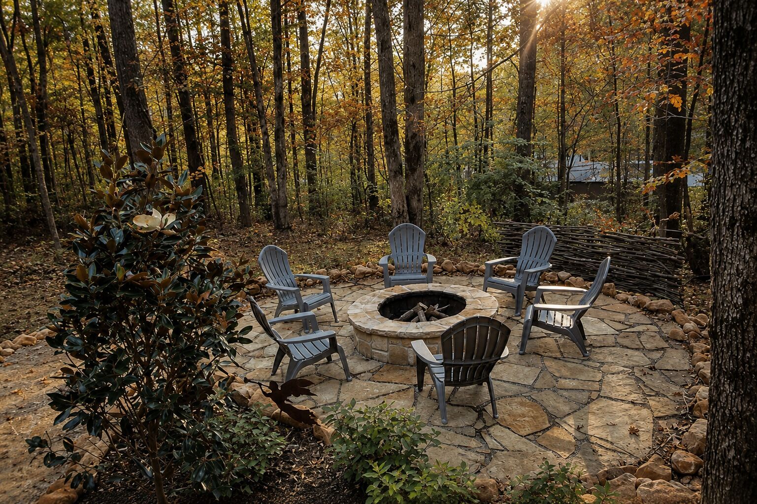 An outdoor seating area with stone flooring and Adirondack chairs around a circular stone fire pit.