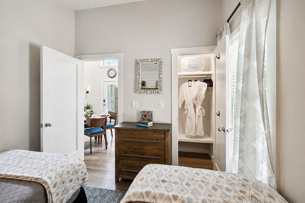 Une chambre avec deux lits, une commode, un miroir et un placard contenant un peignoir.