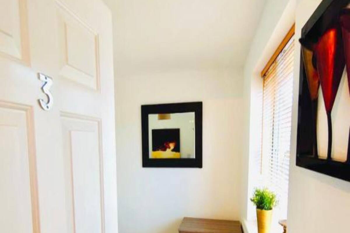 A narrow hallway with a bed, a dresser, and a framed picture on the wall.
