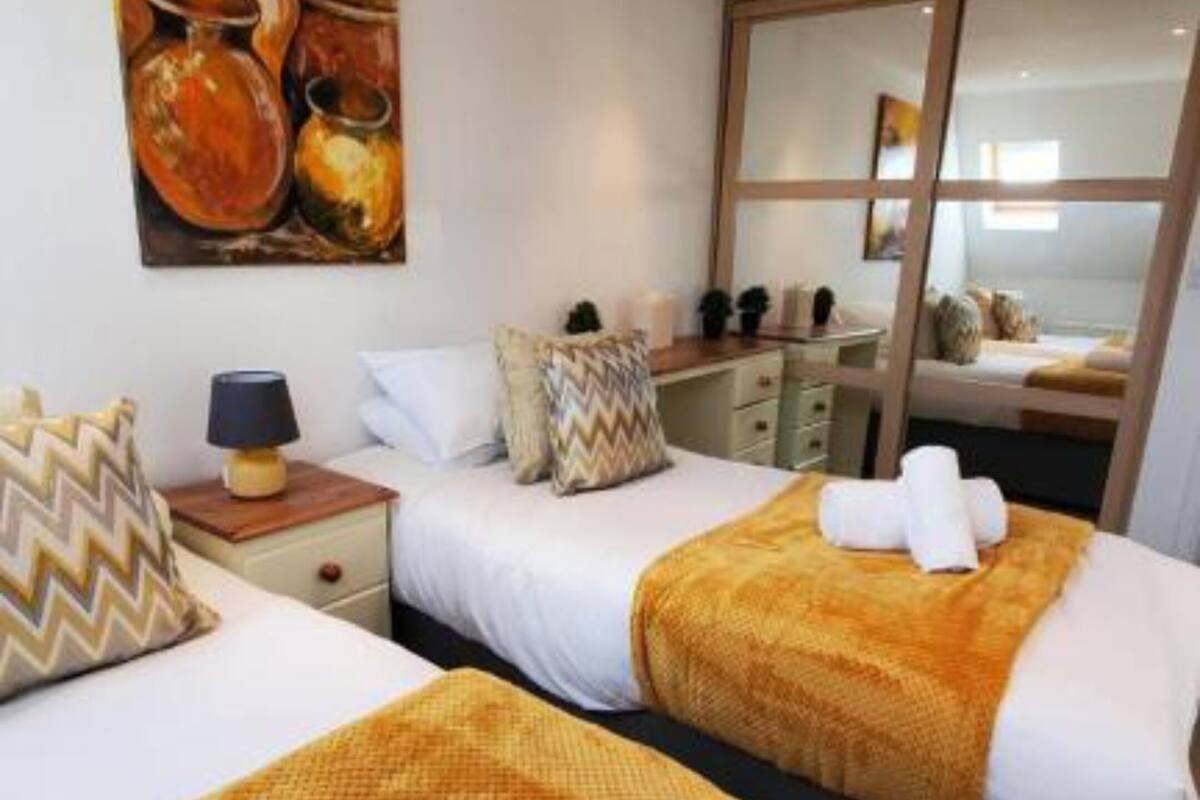 A hotel room with two beds, a painting on the wall, a desk, and a window.