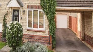 Ein zweistöckiges Backsteinhhaus mit Garage, kleinem Vorgarten und Auffahrt.