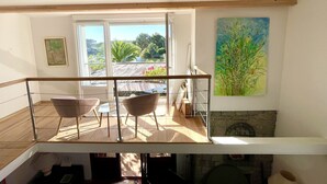 Un balcone con due sedie, un quadro e vista su vegetazione e acqua.