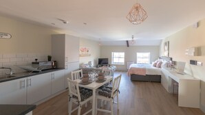 Una camera moderna e luminosa, con zona pranzo, un letto e un angolo studio.