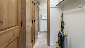 A narrow hallway with wooden doors, a shower area, and a vacuum cleaner on the right. - C305 W Beaver Creek Blvd 2 Bedroom Condo by RedAwning (Avon)