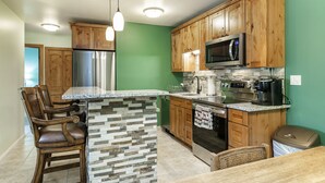 A kitchen with wooden cabinets, a stainless steel refrigerator, a microwave, and a coffee maker. - C305 W Beaver Creek Blvd 2 Bedroom Condo by RedAwning (Avon)