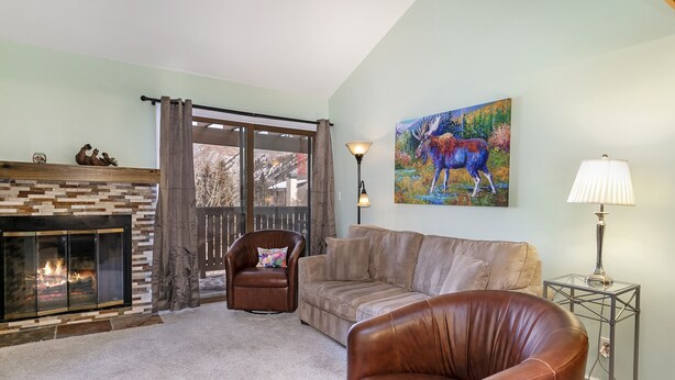 A living room with a fireplace, leather furniture, a painting of a moose, and a lamp. - C305 W Beaver Creek Blvd 2 Bedroom Condo by RedAwning (Avon)