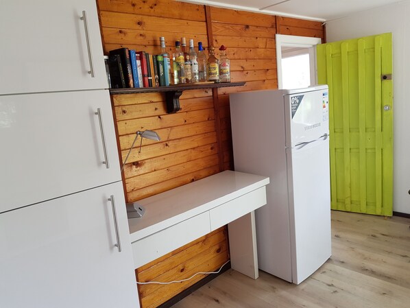 A compact kitchen with white cabinets, a wooden wall, a white countertop, and a white refrigerator. - Oriental Nostalgia in the Cabin Village (exclusive use) - Yacht tour starting at 7 days, including reservation (Groß Köris)