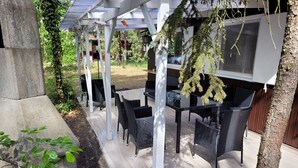 An outdoor patio with black wicker furniture, a pergola structure, and a view of a residential area. - Eastern Nostalgia in the Cabin Village (exclusive use) - Yacht tour starting at 7 days, booking included (Groß Köris)