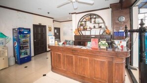 A reception area with a wooden counter, a ceiling fan, a Pepsi vending machine, and a clock on the wall. - Phuket Paradise Hotel (Patong)