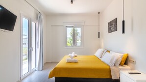 A hotel room with a bed, a TV, a window, and a nightstand.