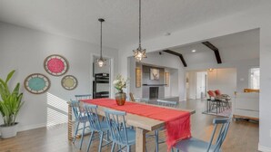 A spacious dining area with a long wooden table, blue chairs, and hanging star-shaped pendant lights. - Dream Vacation Home with Pool for Large Groups! (Garland)