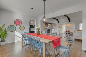A dining area with a wooden table, blue chairs, and hanging star-shaped lights. - Dream Vacation Home with Pool for Large Groups! (Garland)