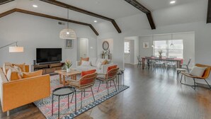 A spacious living room with a large TV, comfortable seating, and a dining area with a table and chairs. - Dream Vacation Home with Pool for Large Groups! (Garland)