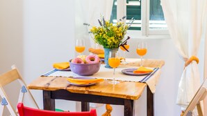 A dining table with a bowl of donuts, a vase of flowers, and glasses of orange juice. - Apartments Eos & Vespera (Dubrovnik)